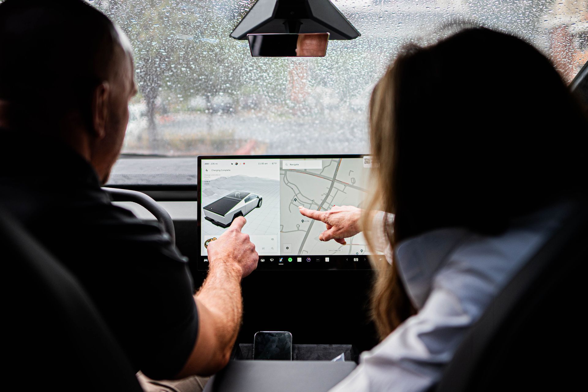 EV technician providing car charger training inside an electric vehicle, explaining charging status and navigation features on the touchscreen display.