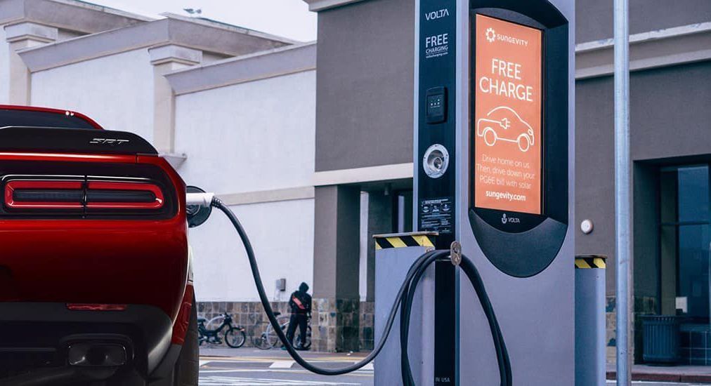 A red car is being charged at a charging station.