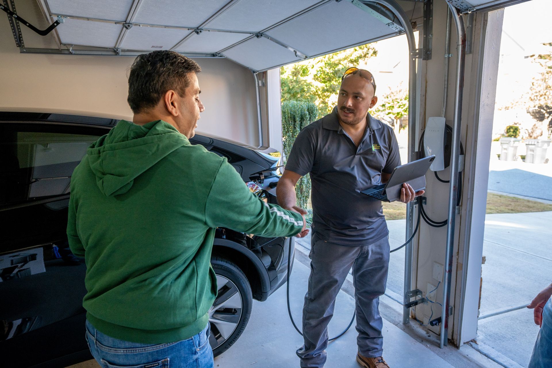 Homeowner shaking hands with an electrician after installing a Level 2 EV charger in a garage