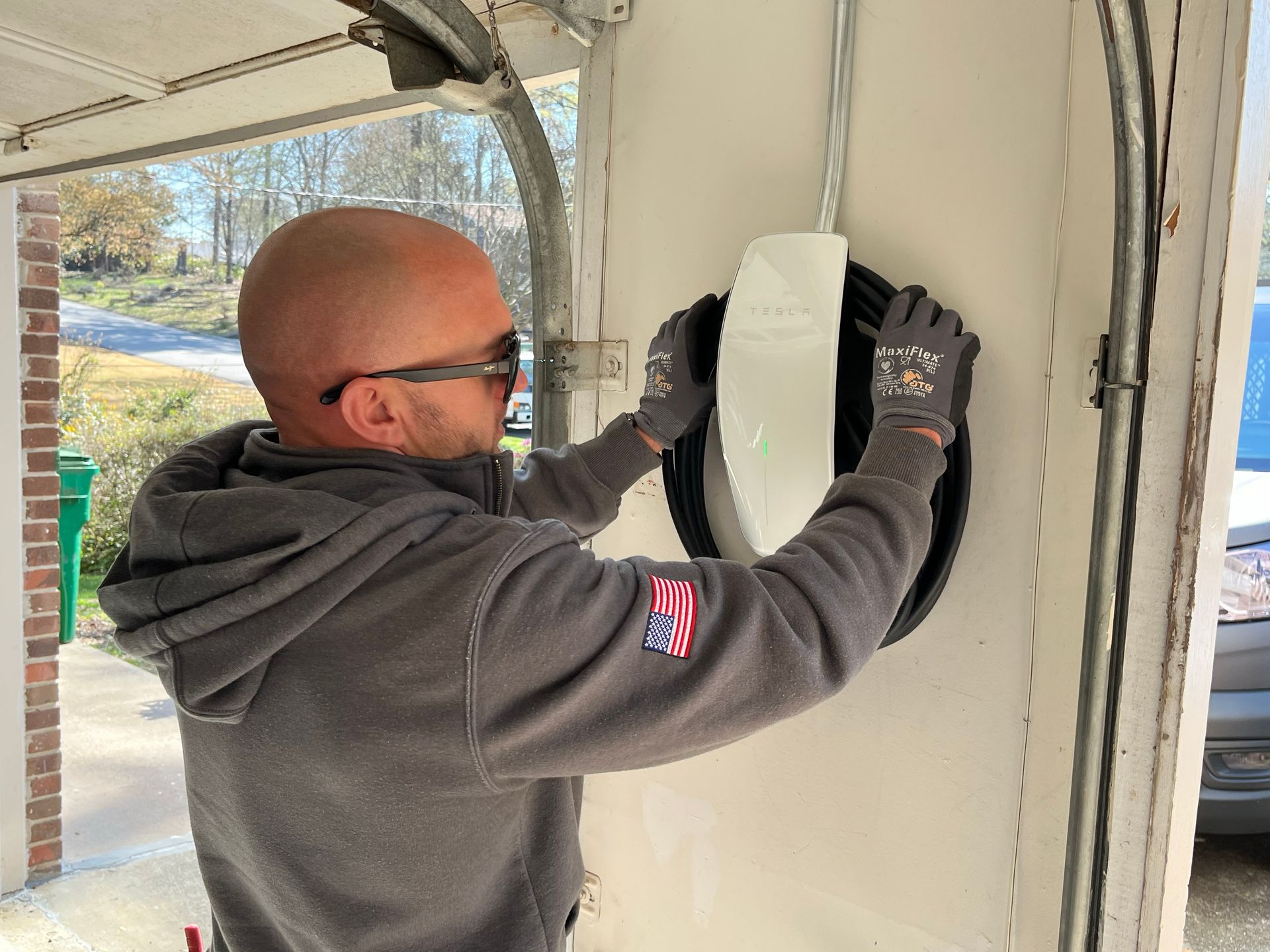 A man in a gray hoodie is working on a garage door.