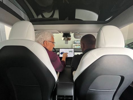 Two men are sitting in the back seat of a tesla model 3