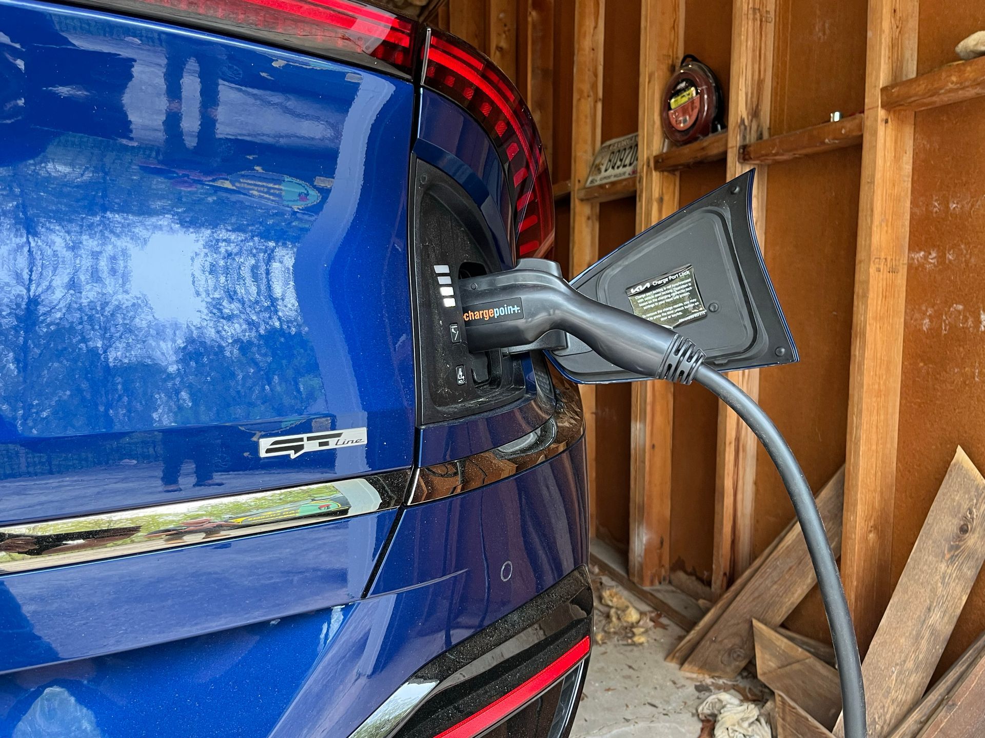A blue car is being charged in a garage.