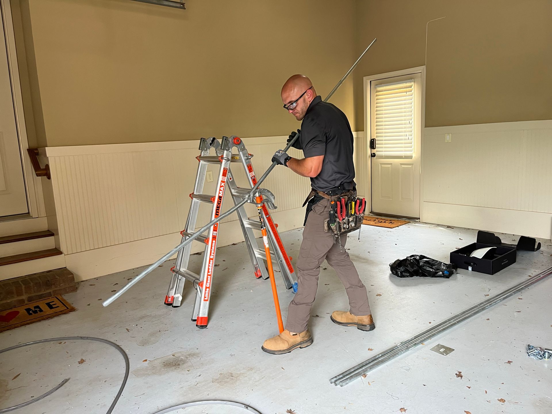 A man is working on a ladder in a garage.