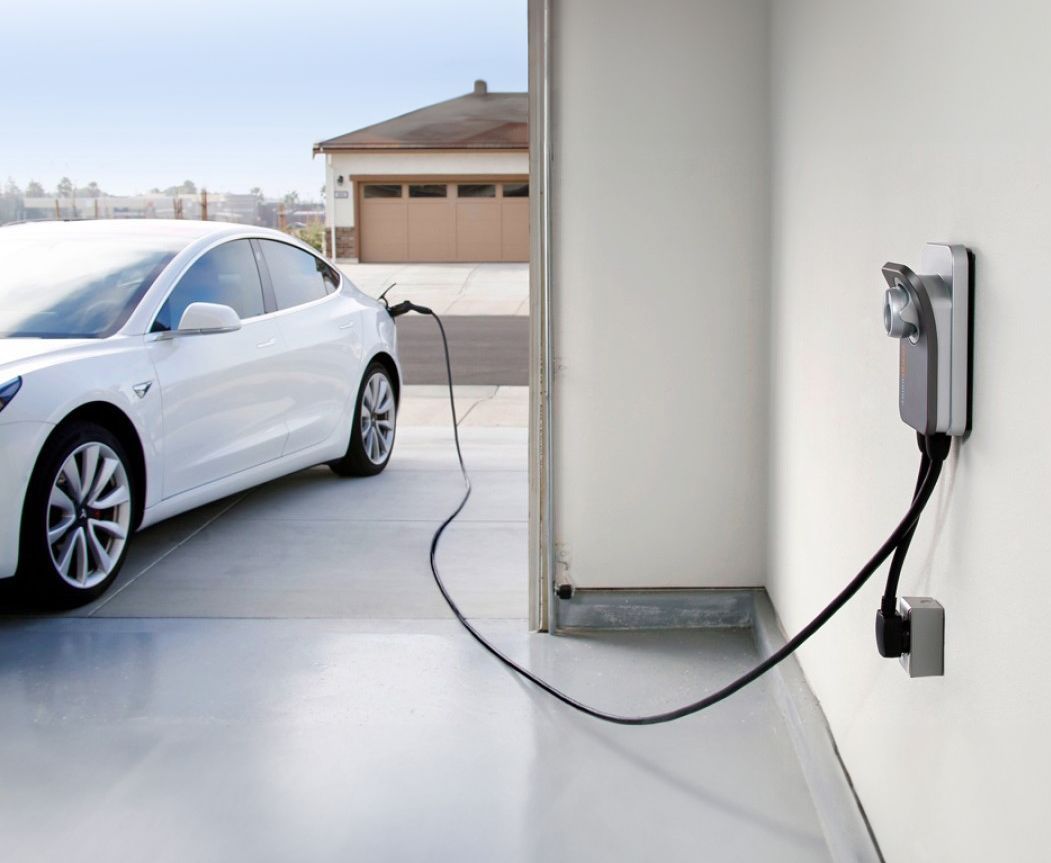 A white electric car is being charged in a garage.