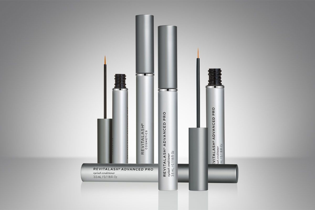 Cosmetic product tubes with applicators, in various heights, on a gradient gray background.