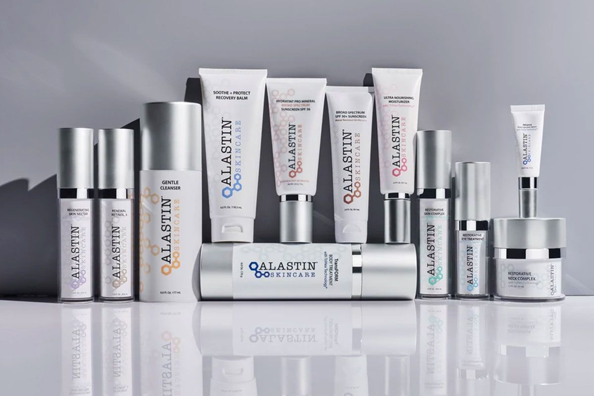 Various Alastin skincare product containers arranged on a reflective surface.