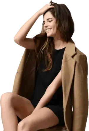 A woman in a black dress and a brown jacket is sitting on a chair.