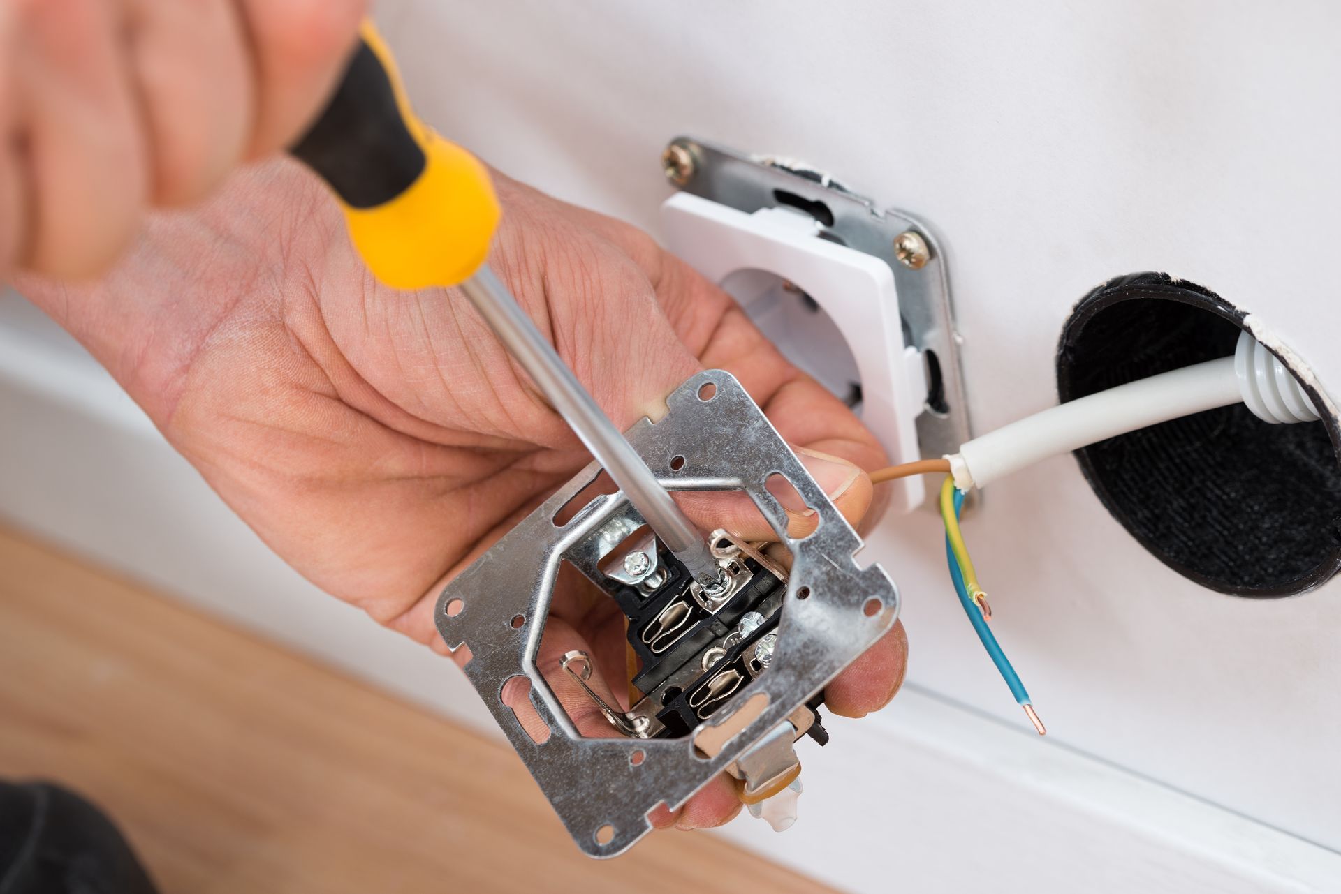 Person using a screwdriver to install an electrical outlet.