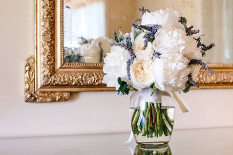 A vase filled with white flowers is sitting on a table in front of a mirror.