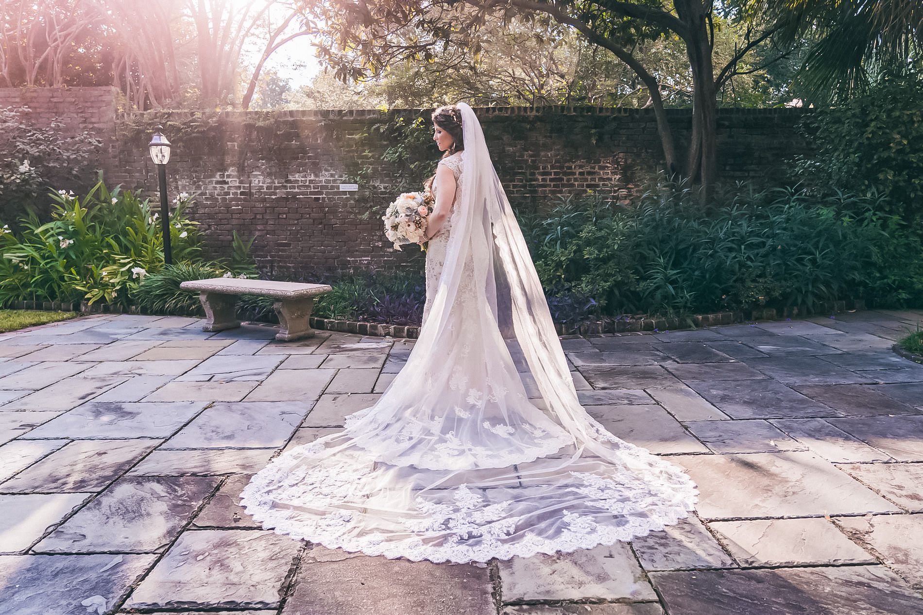 The bride is wearing a long veil and holding a bouquet of flowers.
