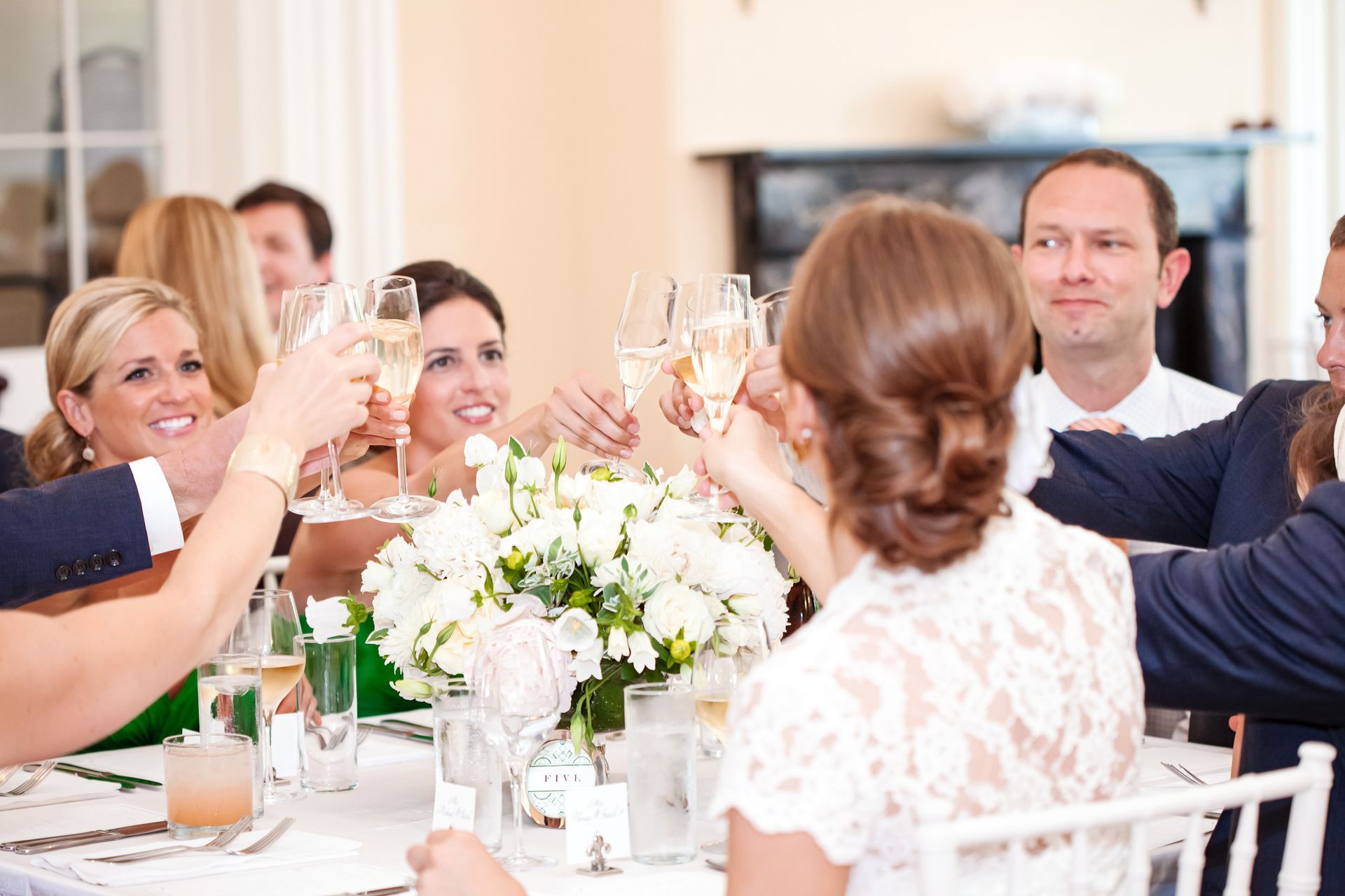 A group of people are sitting at a table toasting with champagne glasses.
