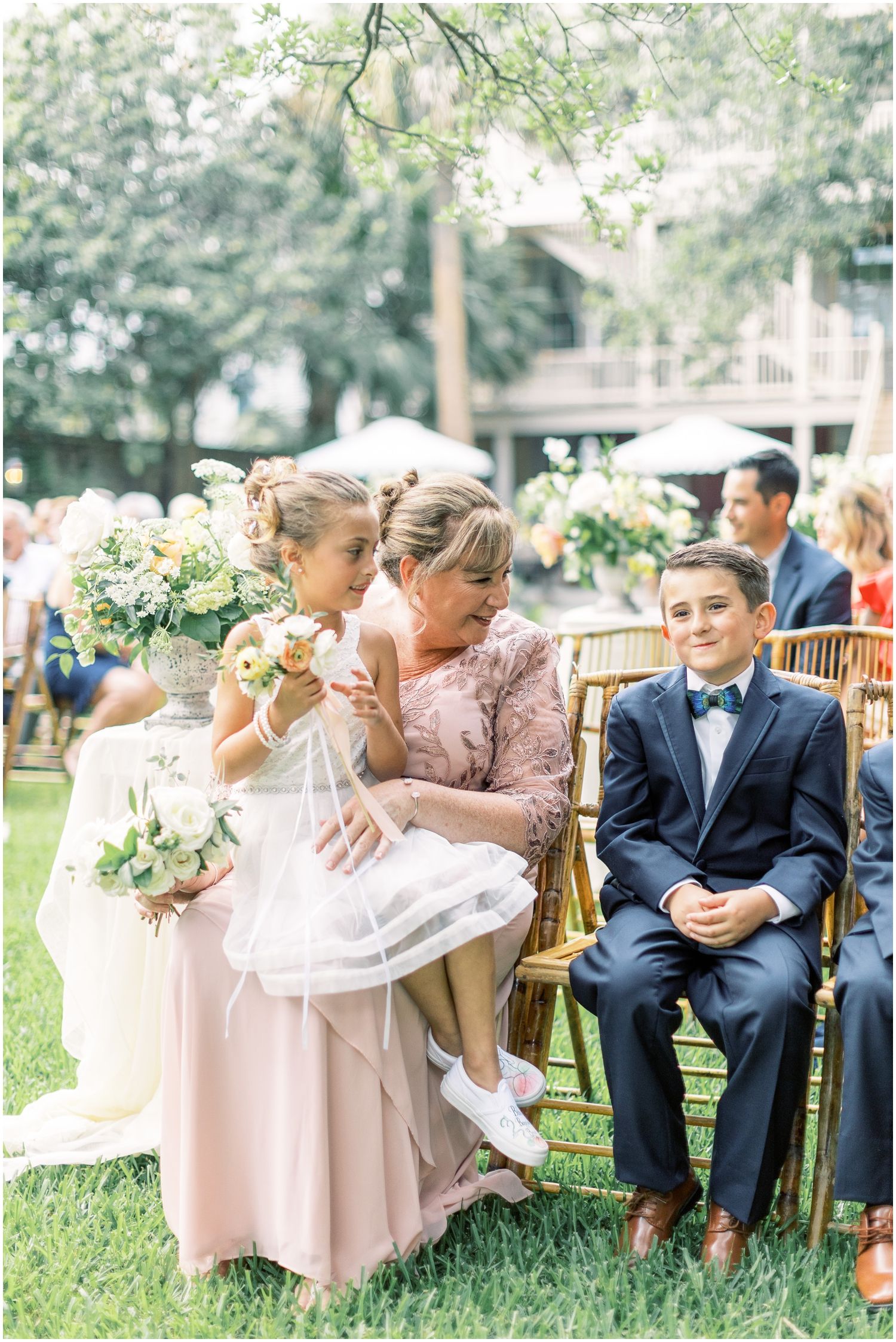 A flower girl is sitting on a woman 's lap at a wedding ceremony.