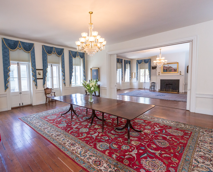 A dining room with a long table and a red rug