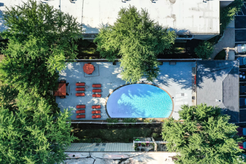 an aerial view of a swimming pool surrounded by trees and chairs .