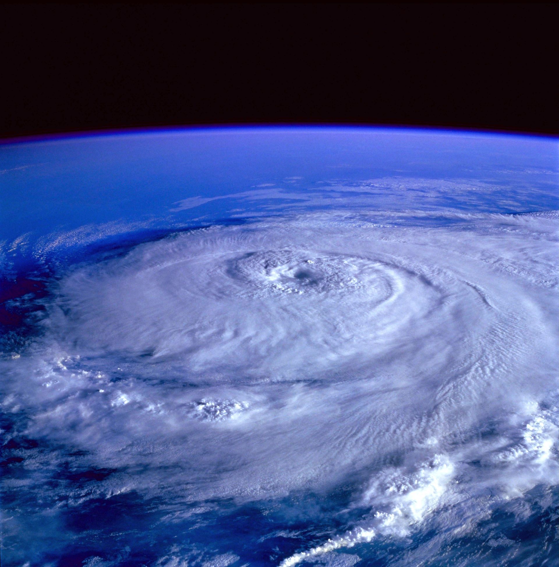 Satellite view of a large swirling hurricane over the ocean, with a clear eye and cloud bands
