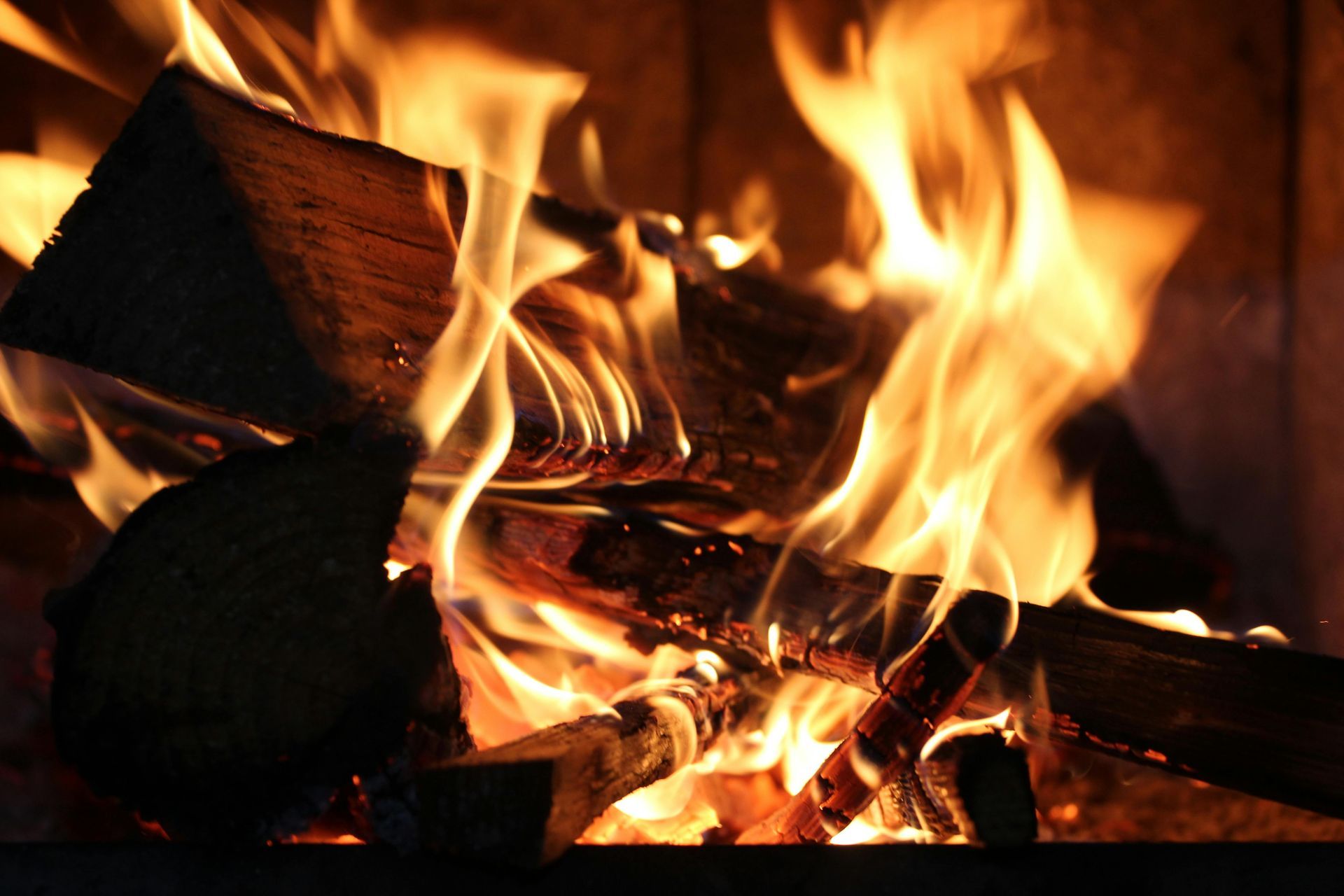 Burning firewood in a fireplace, flames are orange and yellow.