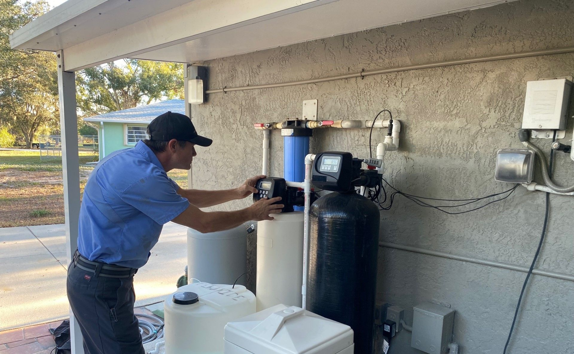 Man adjusting water filtration system outside a building.