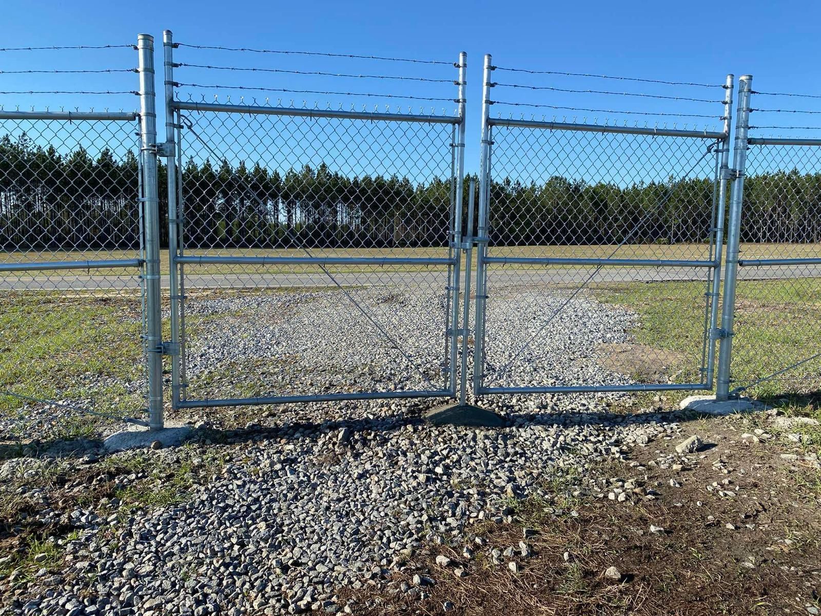 Chain link gate with barbed wire atop. 