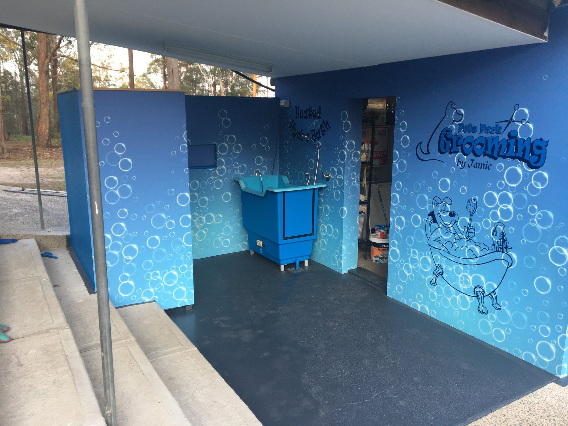 Blue dog washing station with a tub, steps, and bubble-themed art.