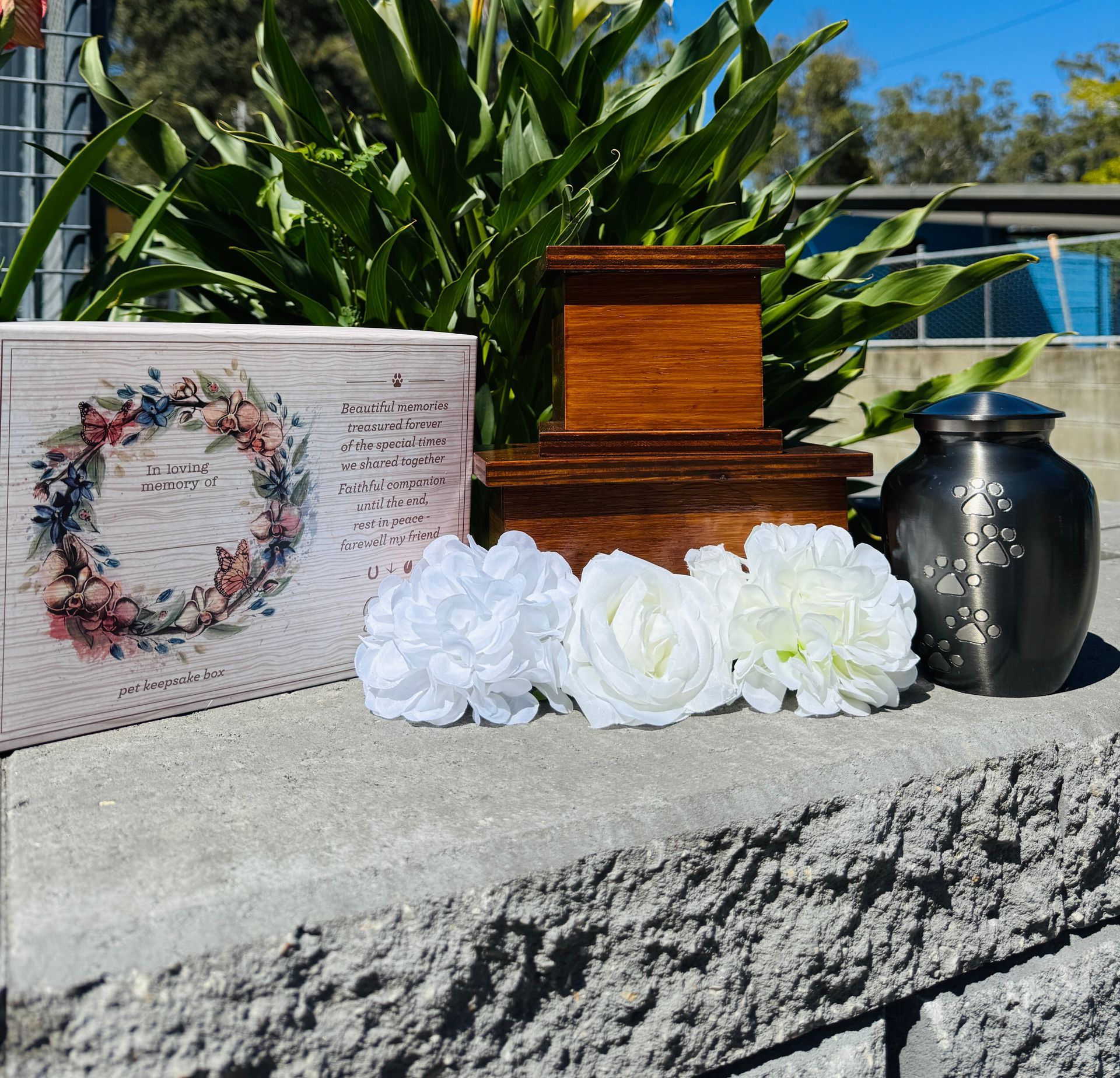 Pekingese dog photo in a frame next to a pet cremation urn with paw prints.