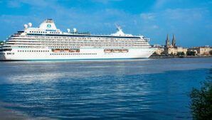 A large cruise ship is docked in the water near a city.