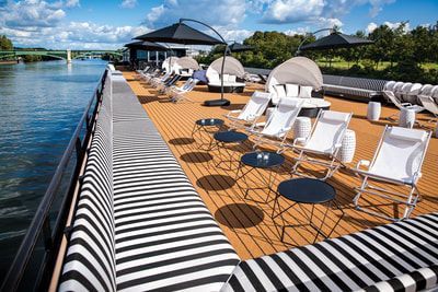 There are a lot of chairs and tables on the deck of a boat.