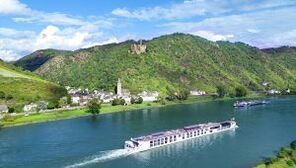 A large cruise ship is sailing down a river surrounded by mountains.