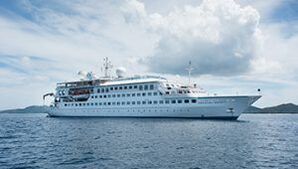 A large white cruise ship is floating on top of a body of water.