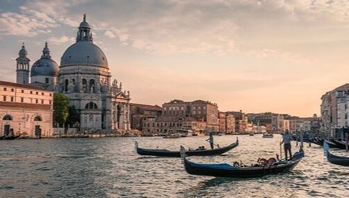 A couple of gondolas are floating on a river in venice.