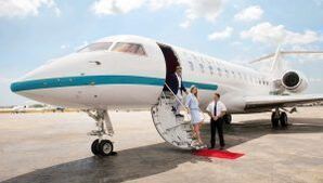 A woman is boarding a private jet on a red carpet.