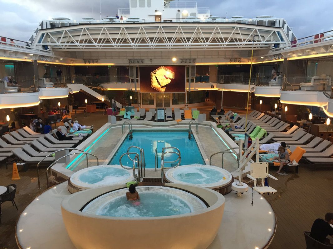 A large cruise ship with a swimming pool and hot tubs on the deck.