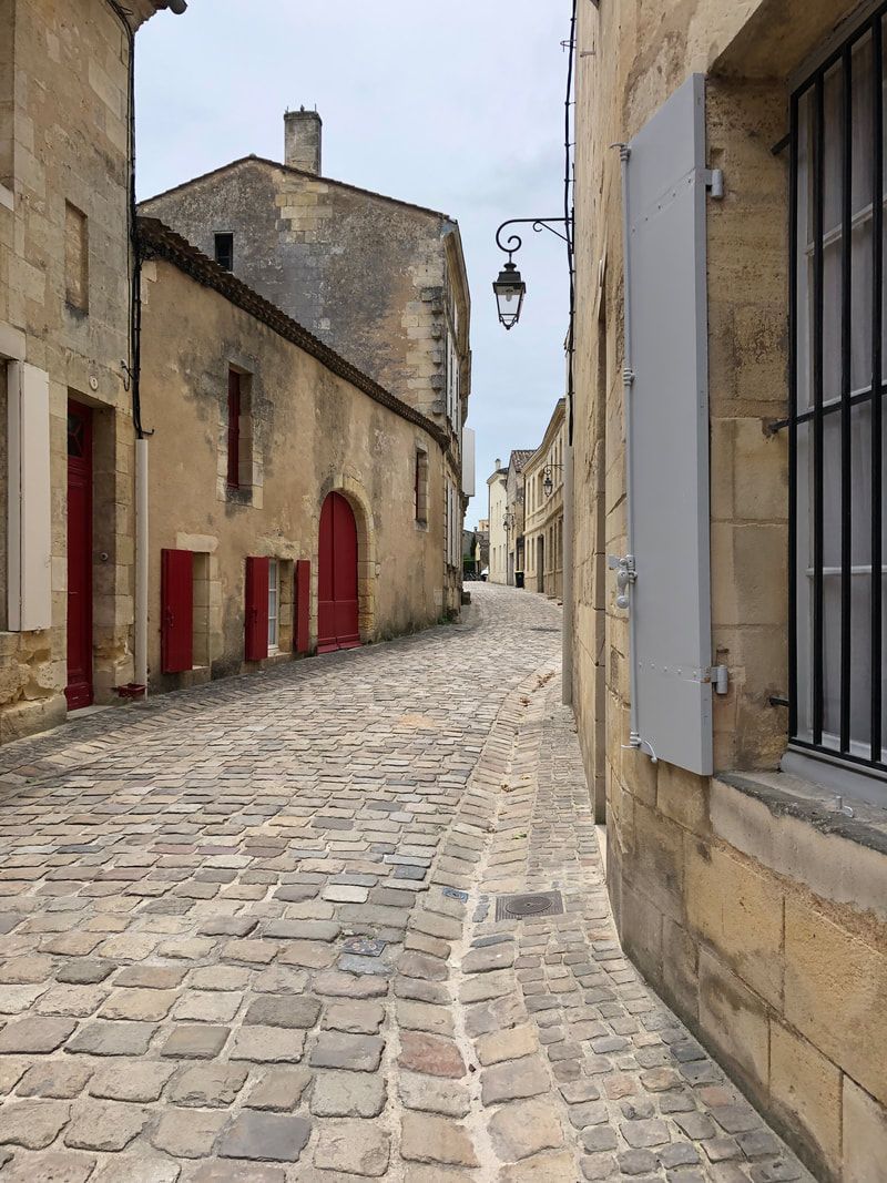 A cobblestone street between two buildings with red doors.