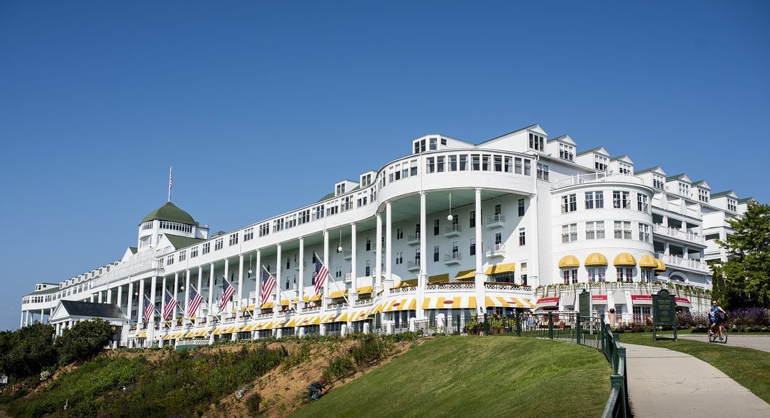 A large white building with a lot of columns is sitting on top of a hill.