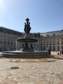 A large fountain in the middle of a square in front of a building.