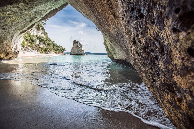 A view of a beach from inside a cave.