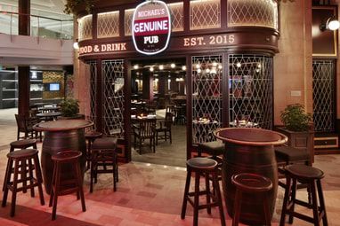 A restaurant with tables and stools in front of it.