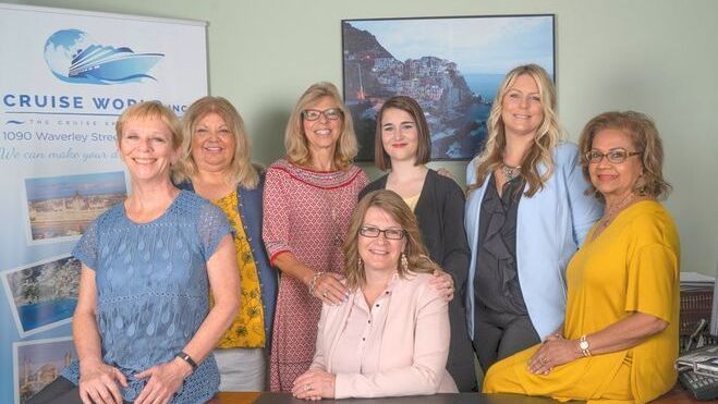 A group of women are posing for a picture in front of a cruise world sign.