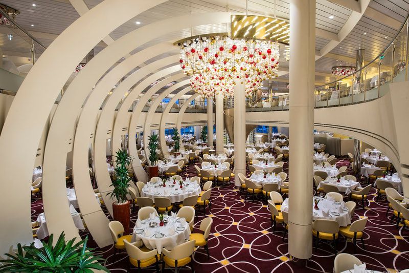 A large dining room with tables and chairs and a large chandelier.