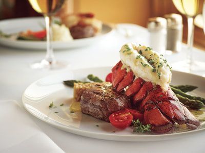 A white plate topped with a steak and lobster tail