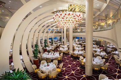 A large dining room with tables and chairs and a chandelier hanging from the ceiling.