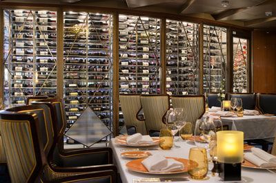 A restaurant with tables and chairs and a wall of wine bottles.