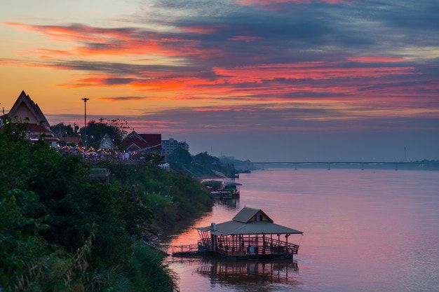 A boat is floating on a river at sunset.