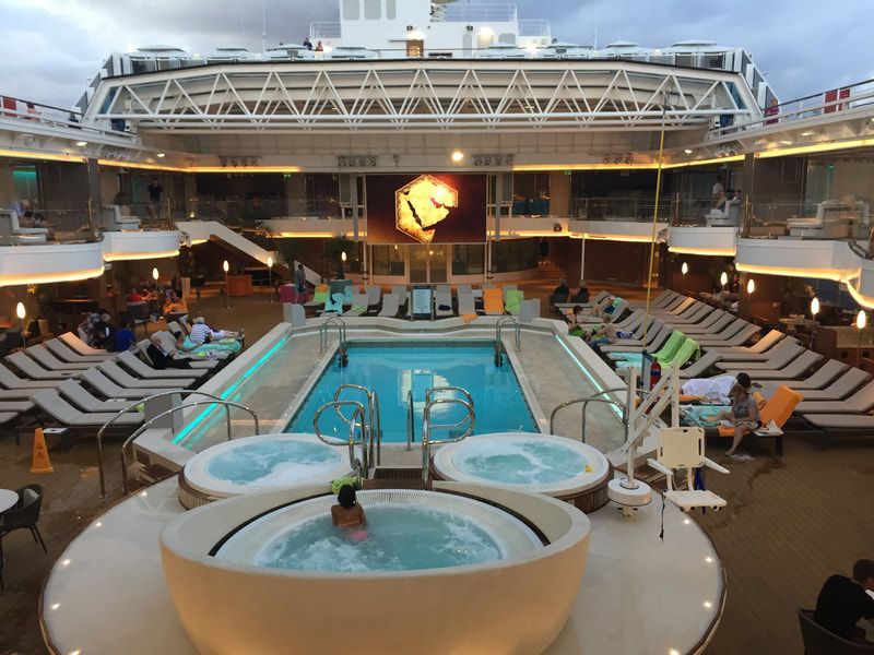 A large cruise ship with a large swimming pool and hot tubs.