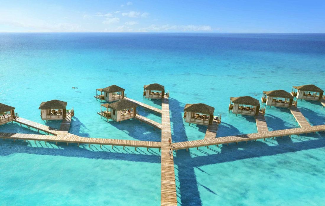 An aerial view of a row of bungalows on a dock in the middle of the ocean.