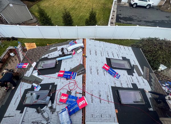 Rooftop with several skylights and roofing materials in the process of being installed.