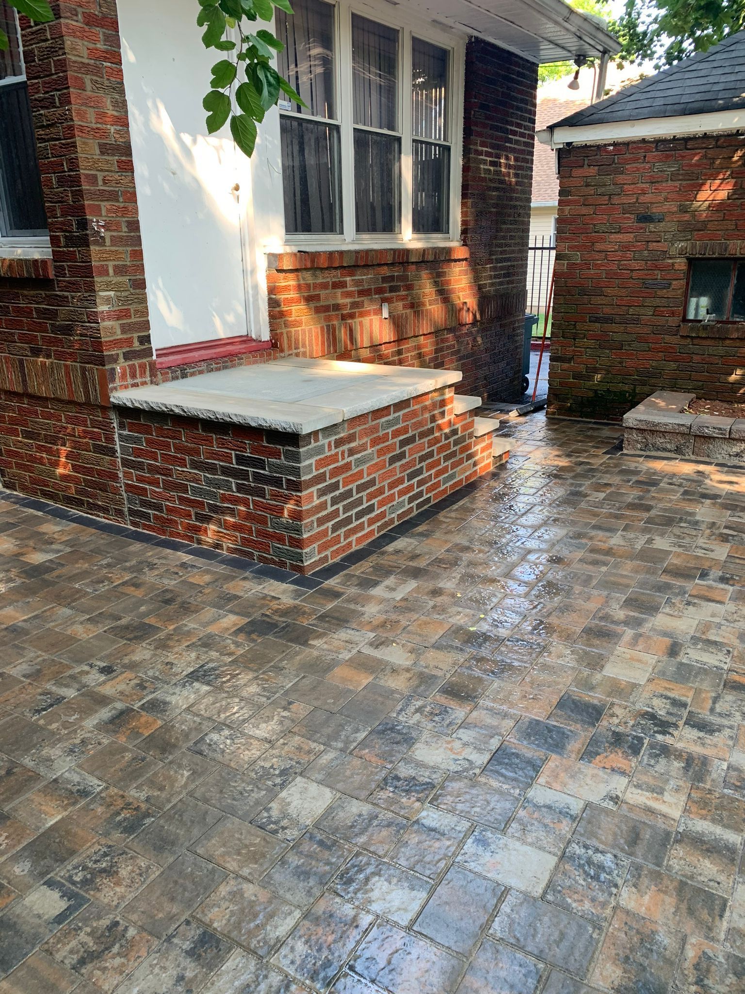 Brick paved patio next to a brick building with a raised brick entrance and a small brick structure.