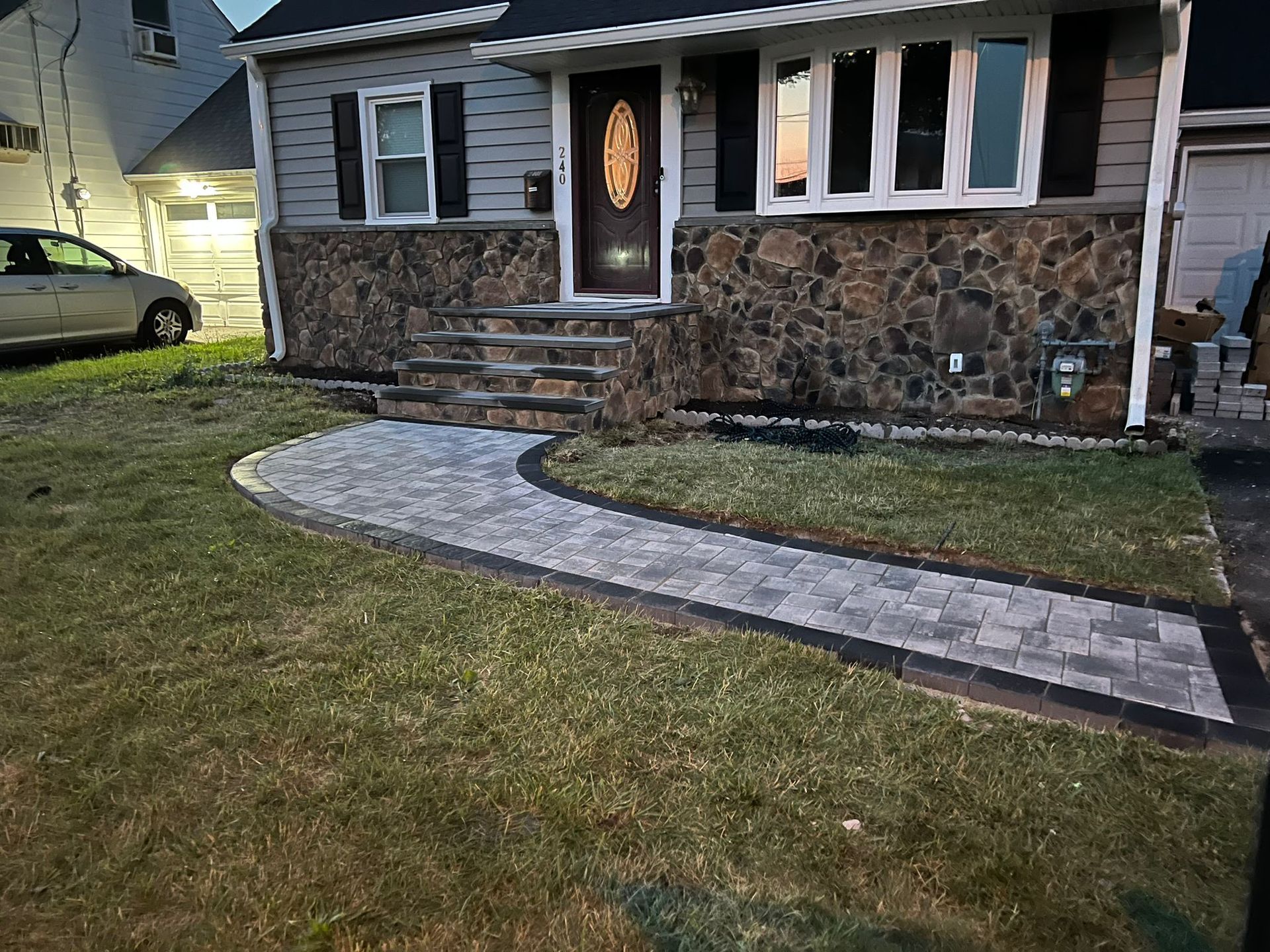 A house with a newly paved walkway and stone accent. The path curves towards the front door.