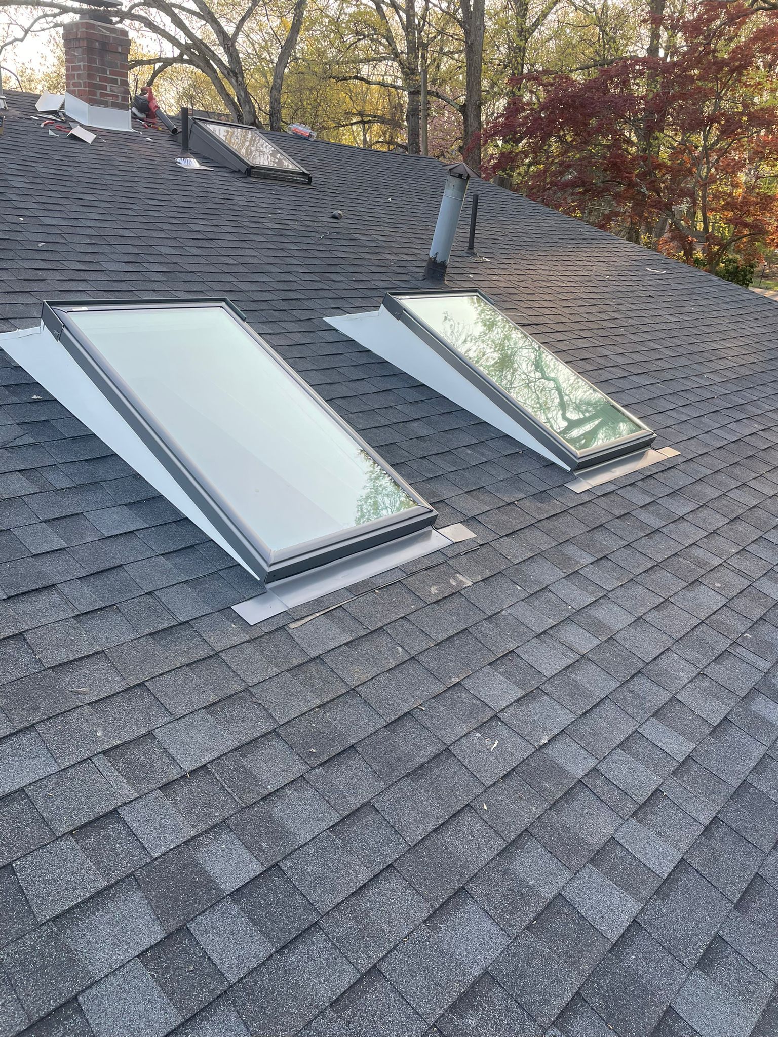 Two rectangular skylights on a dark gray shingled roof. White flashing surrounds the skylights.