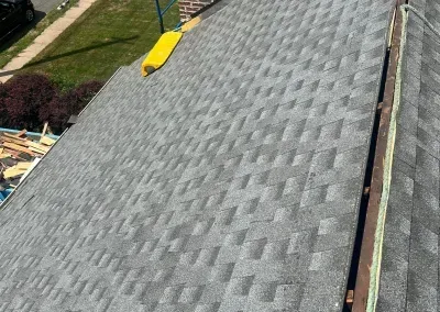 Gray asphalt shingle roof with a yellow gutter cleaner on top, angled view.