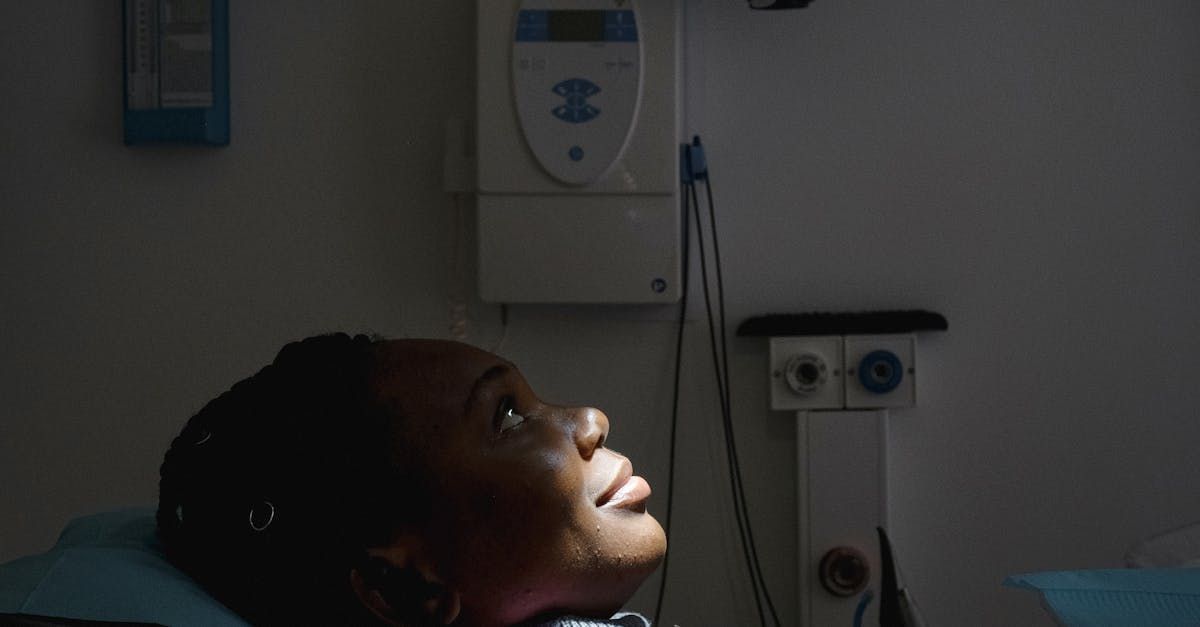 A woman is laying in a dental chair in a dark room looking up.